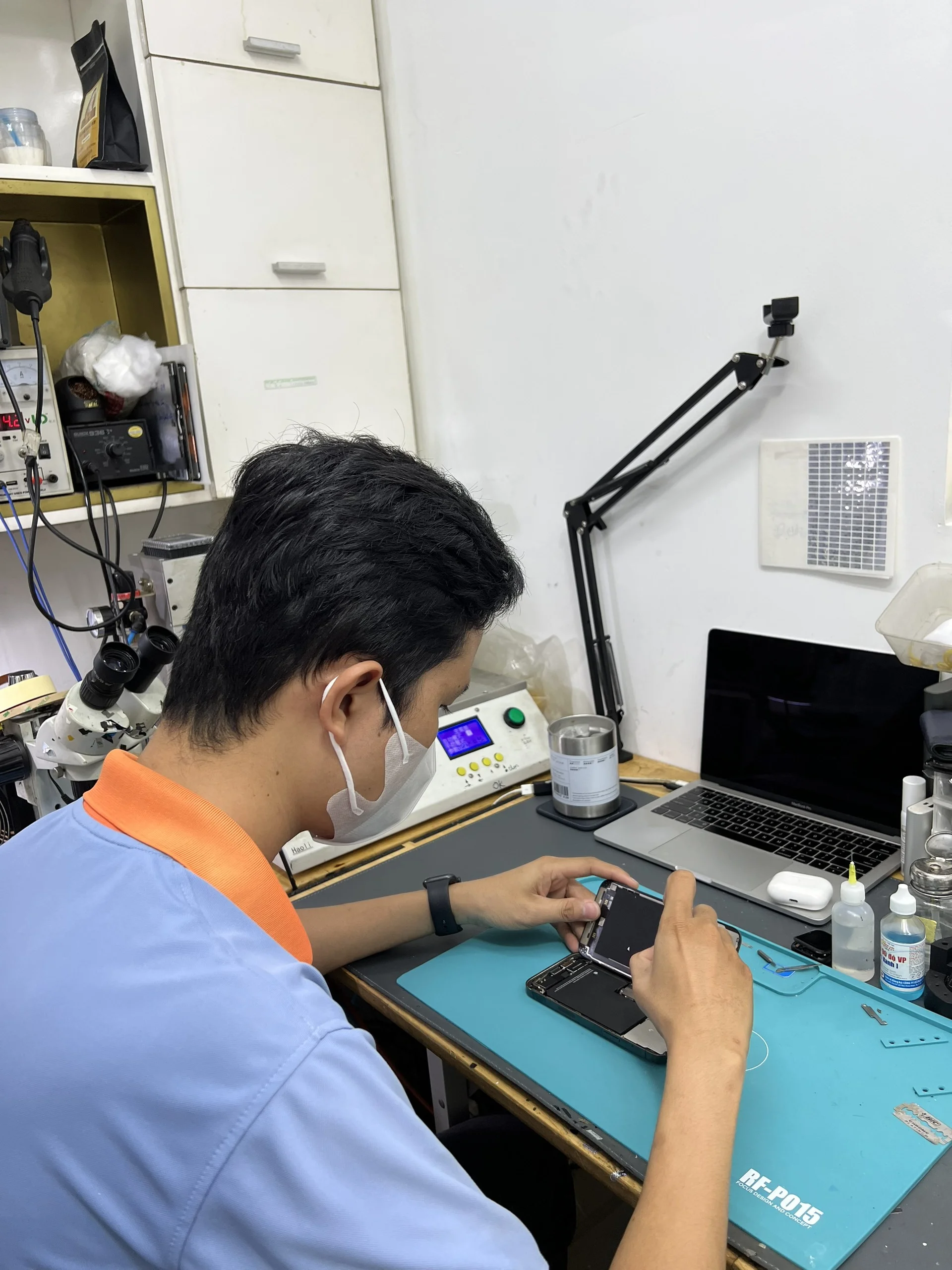 Kỹ thuật viên sửa điện thoại đang thực hiện sửa cho khách