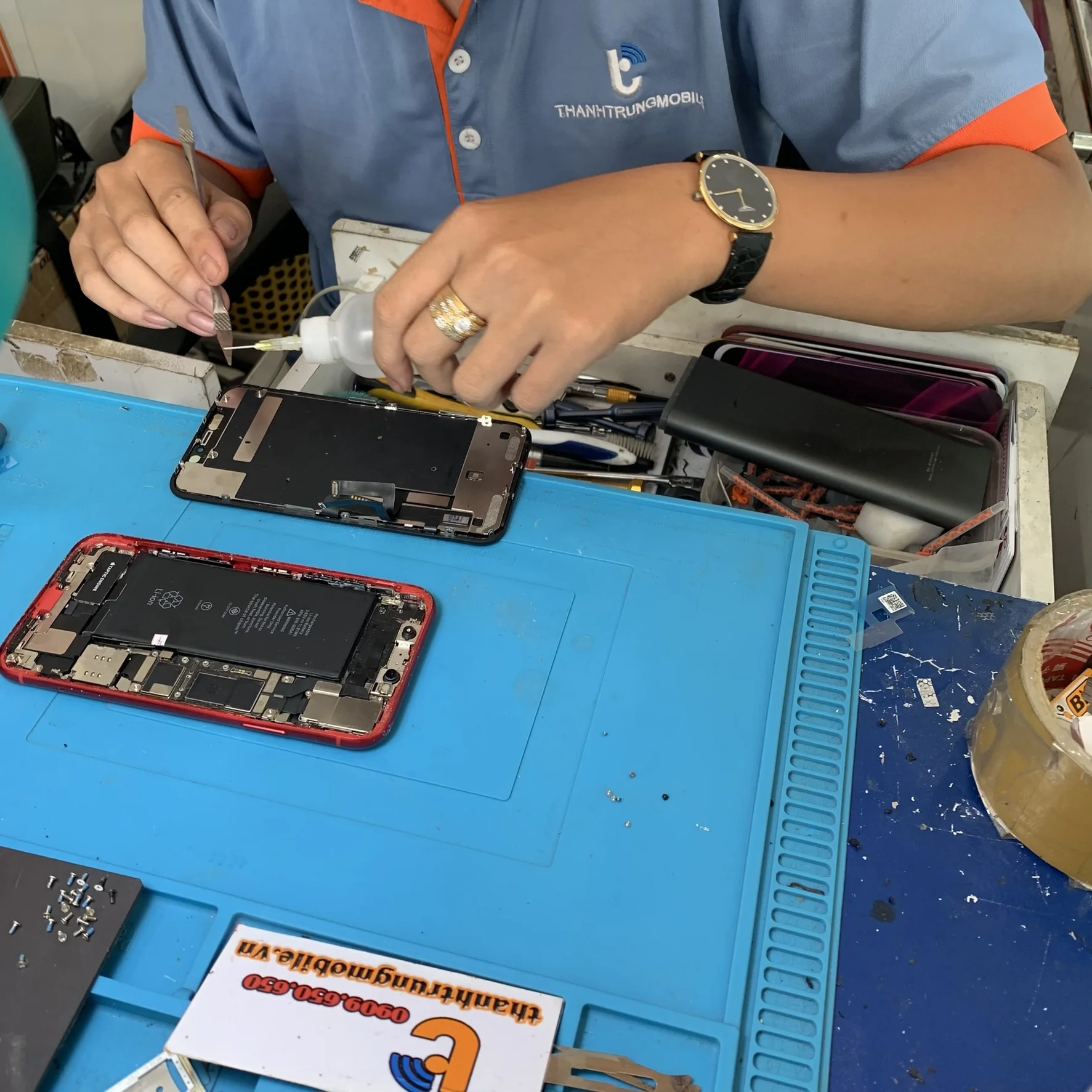 Thợ sửa điện thoại thao tác thay pin iPhone 15 Pro Max